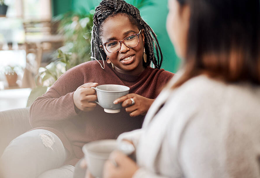 two friends sitting on the couch drinking coffee